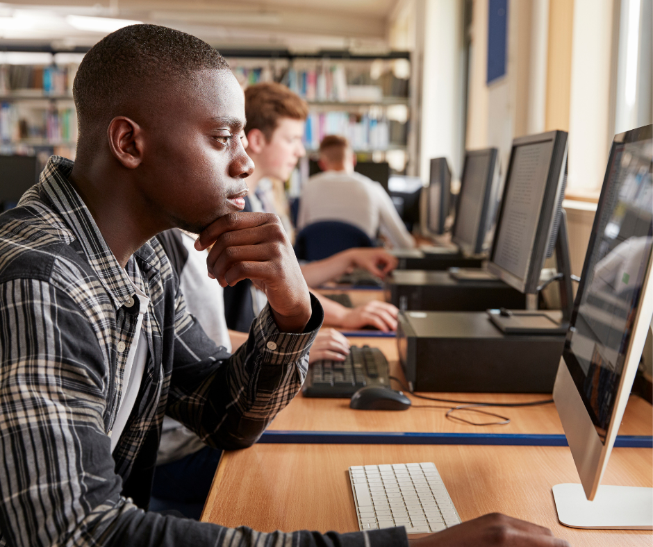 Focused young man working at a computer in a library.