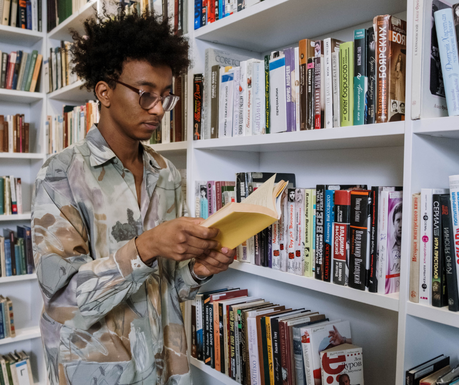Young man reading a book in a library.