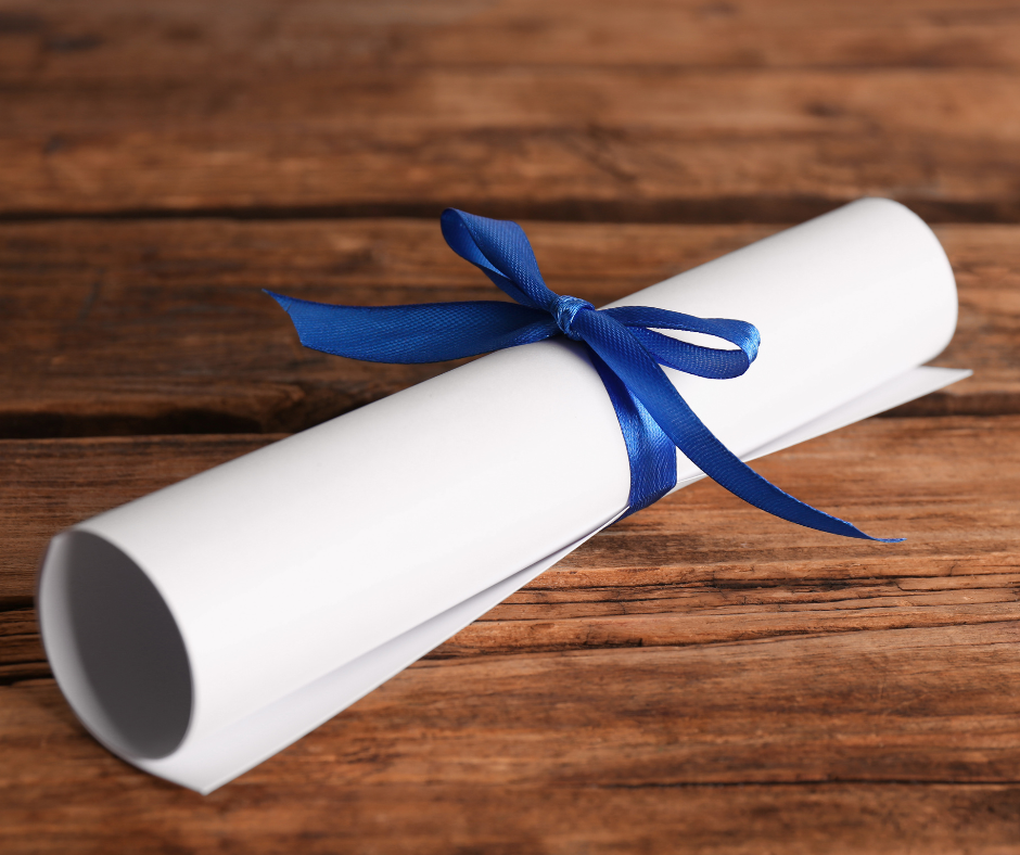 Rolled diploma tied with a blue ribbon on a wooden surface.