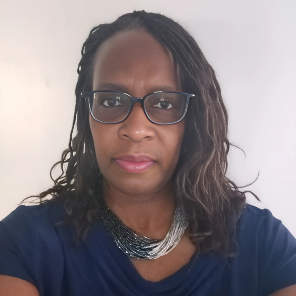 Catherine Banks-Moore wearing glasses and a navy blouse, looking at the camera against a neutral background.